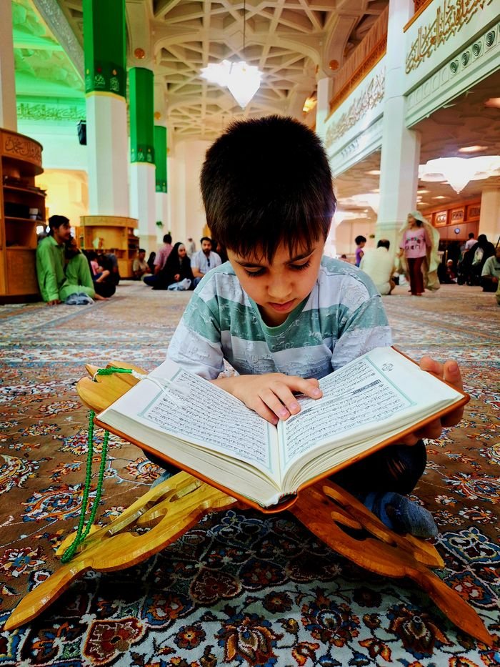 digital A young boy deeply engrossed in reading the Quran inside a mosque in Qom, Iran.